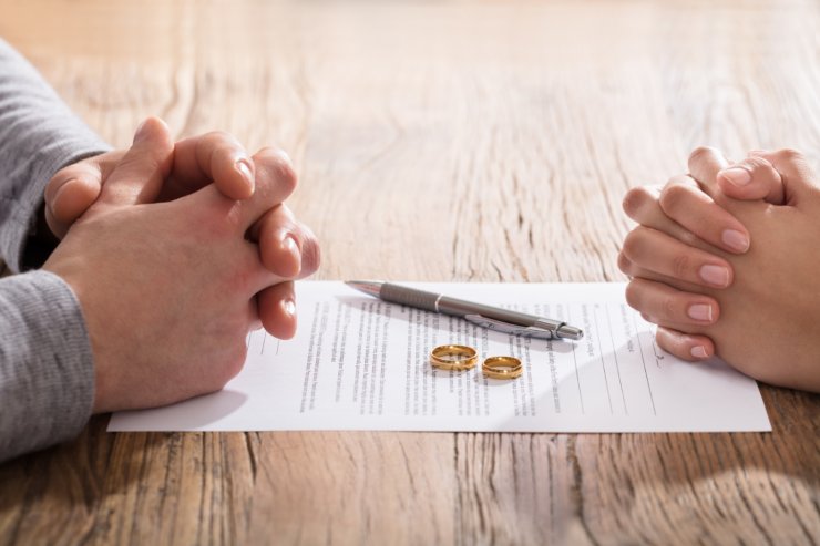 fedi matrimonio e penna su documento divorzio e mani marito e moglie