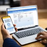 uomo con smartphone di fronte a home banking su pc